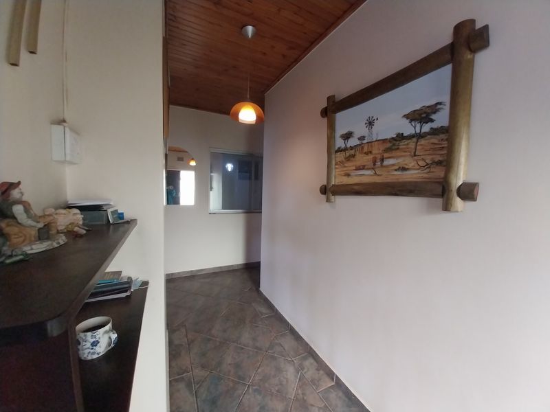 A functional hallway featuring tiled flooring, a timber-paneled ceiling, and built-in shelving, providing a warm and practical transition space within the home.