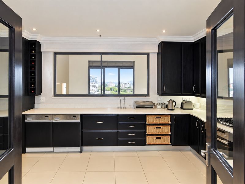 Modern kitchen featuring dark cabinetry, stone countertops, integrated appliances, and a built-in wine rack, complemented by recessed lighting and tiled flooring.