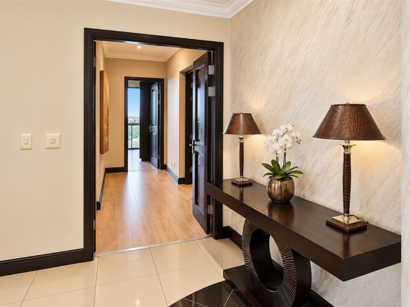 A well-maintained hallway featuring polished tile flooring, a textured feature wall, and dark wood door frames leading to an adjacent corridor.