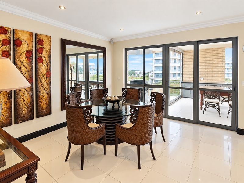 A bright dining room featuring tiled flooring, recessed downlights, and large sliding glass doors that provide access to an outdoor patio area.