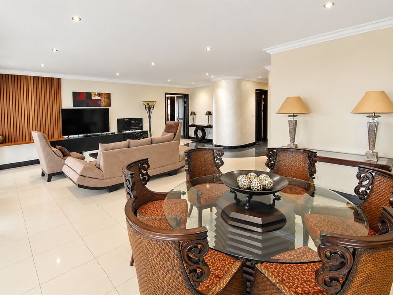 Spacious open-plan living and dining area featuring polished tiled floors, recessed lighting, and a decorative timber slat wall feature.