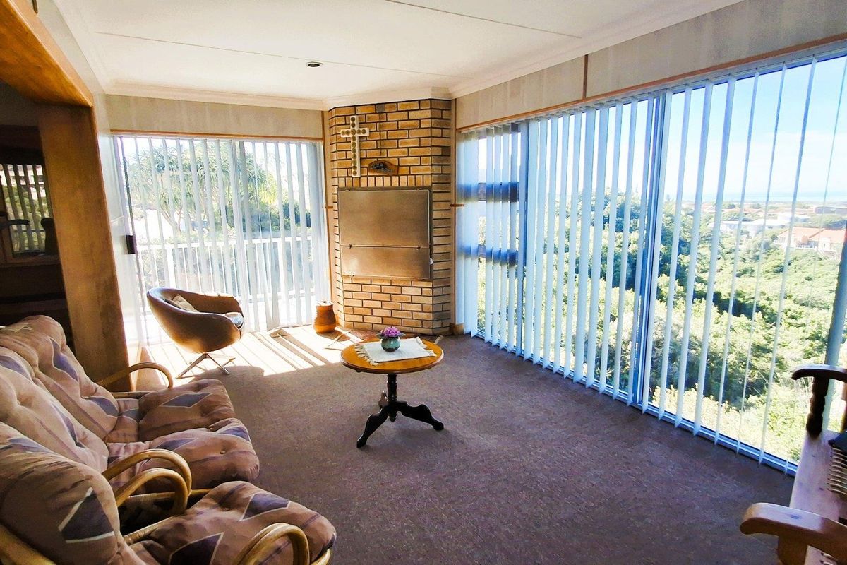 Spacious living area featuring a built-in brick fireplace and expansive sliding glass doors with vertical blinds, offering abundant natural light and scenic views.