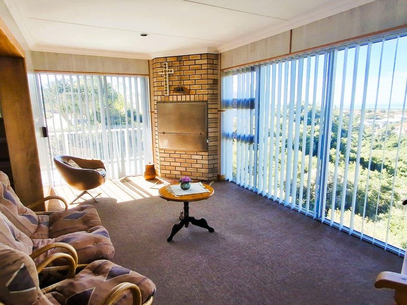Spacious living area featuring a built-in brick fireplace and expansive sliding glass doors with vertical blinds, offering abundant natural light and scenic views.
