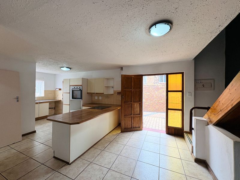 Open-plan kitchen and living area featuring tiled floors, built-in cabinetry, and direct access to an outdoor patio area.