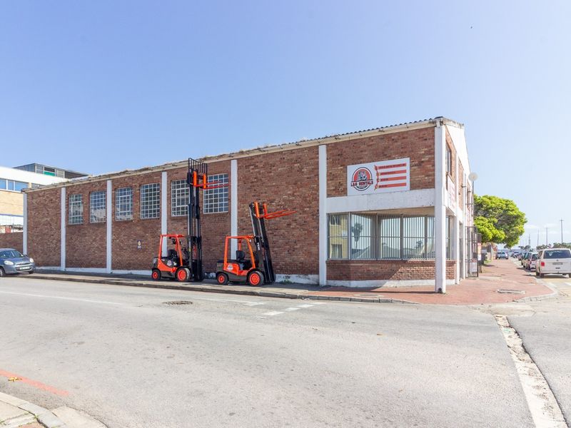 Industrial property featuring an exposed brick facade, steel-framed windows, and a corner office section, situated on a street-facing corner lot.