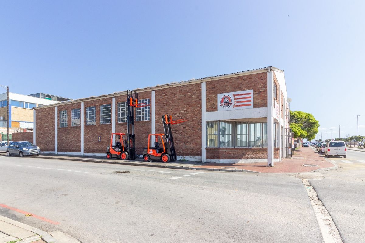 Industrial property featuring an exposed brick facade, steel-framed windows, and a corner office section, situated on a street-facing corner lot.