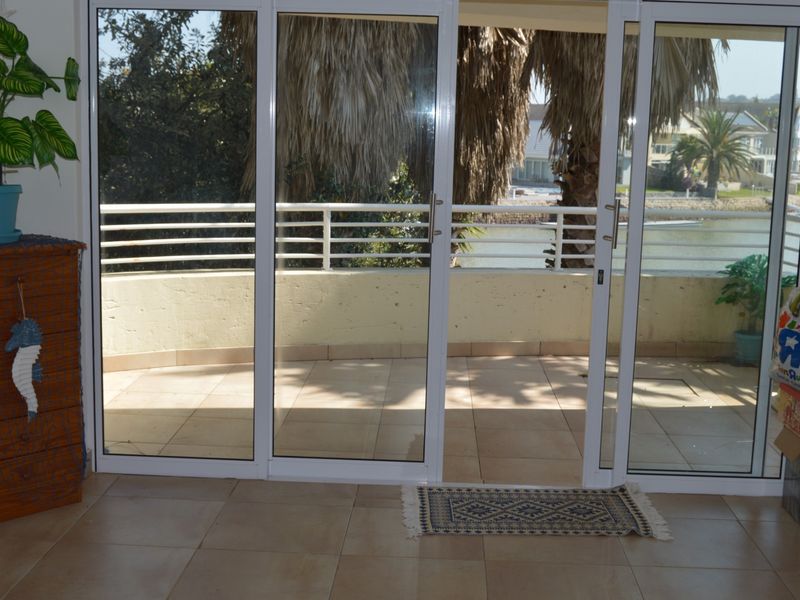 A bright balcony area featuring tiled flooring and a metal balustrade, accessible through large sliding glass doors from the interior living space.