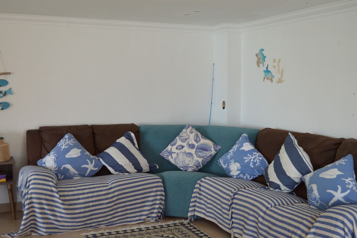 A living room area featuring coving and recessed ceiling lighting, currently styled with a large corner sofa.