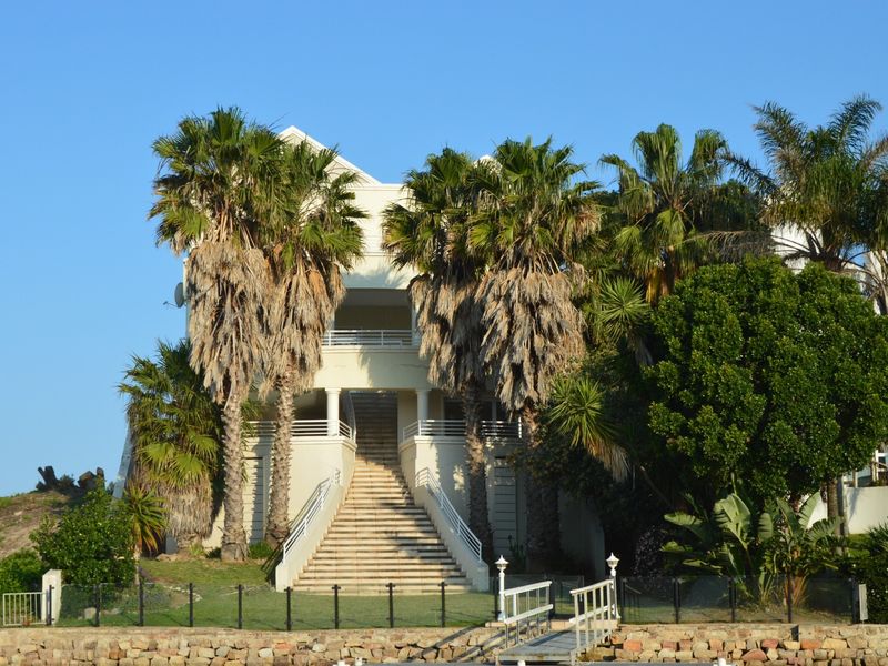 Rear elevation of a multi-story residence featuring a prominent central staircase, stone retaining wall, and balcony access.