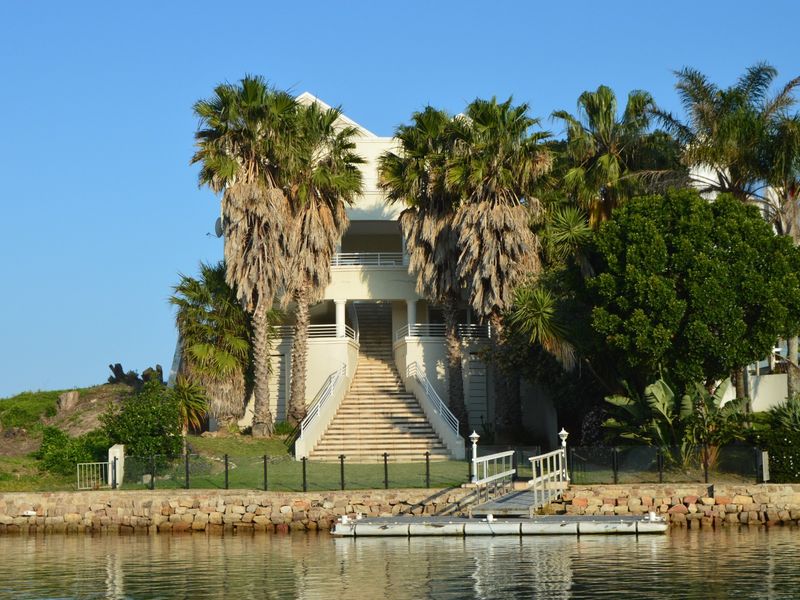 Waterfront property featuring a private jetty, stone retaining wall, and a grand central staircase leading to the main residence.