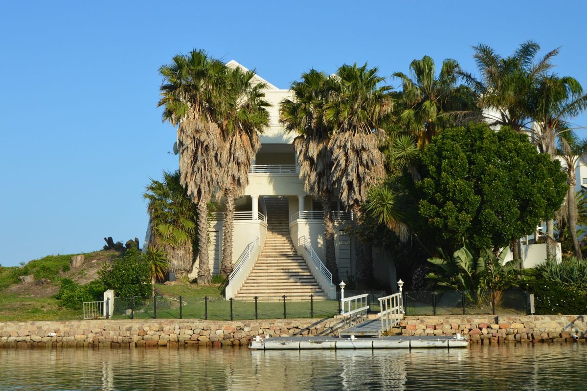 Waterfront property featuring a private jetty, stone retaining wall, and a grand central staircase leading to the main residence.