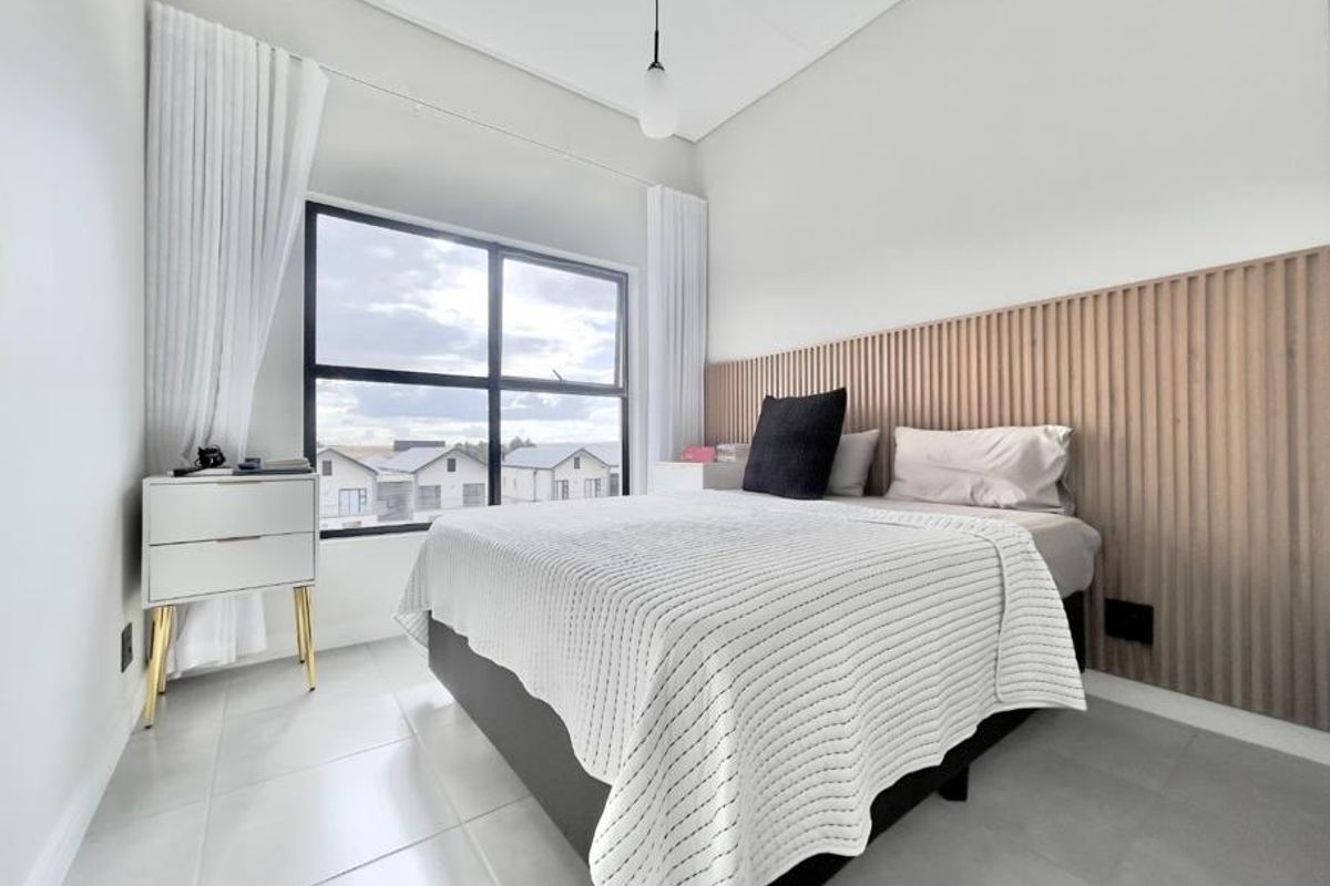 Modern bedroom featuring large windows, contemporary tiled flooring, and a stylish vertical slat wood feature wall behind the bed area.