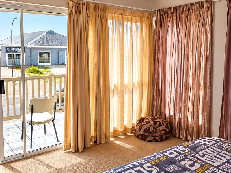 A bedroom featuring carpeted flooring and a sliding glass door that opens onto a private balcony with outdoor tiling and railing.