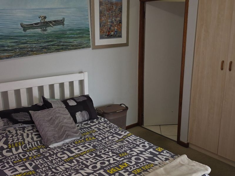 A bedroom featuring a built-in wardrobe with light wood-finish doors and neutral wall tones.