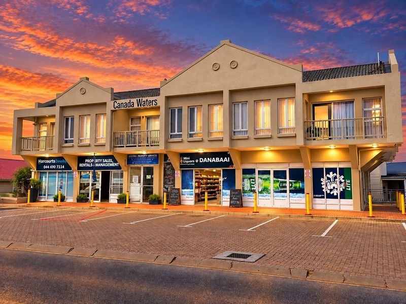 Front elevation of the Canada Waters commercial and residential building featuring ground-floor retail units and upper-level balconies with paved parking.