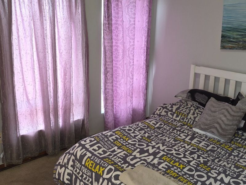 A standard bedroom featuring carpeted flooring and natural light through window treatments.