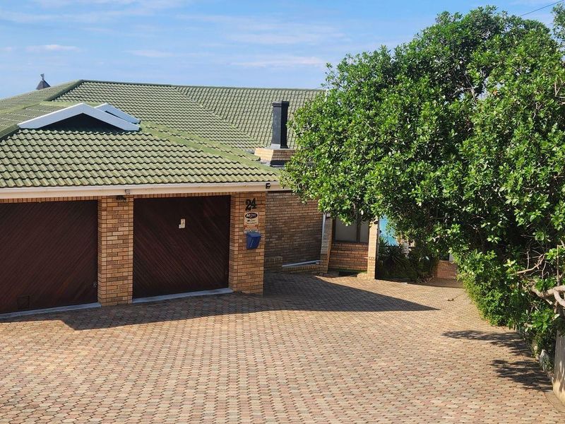 Front elevation of a brick house featuring a double garage, paved driveway, and tiled roof, set in a well-maintained residential area.