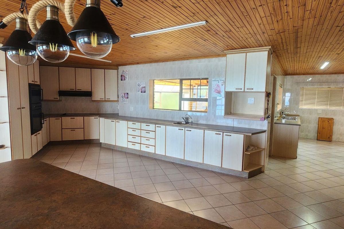 Spacious kitchen featuring extensive built-in cabinetry, laminate countertops, a double sink, and a distinctive timber ceiling, offering a functional layout with ample storage space.