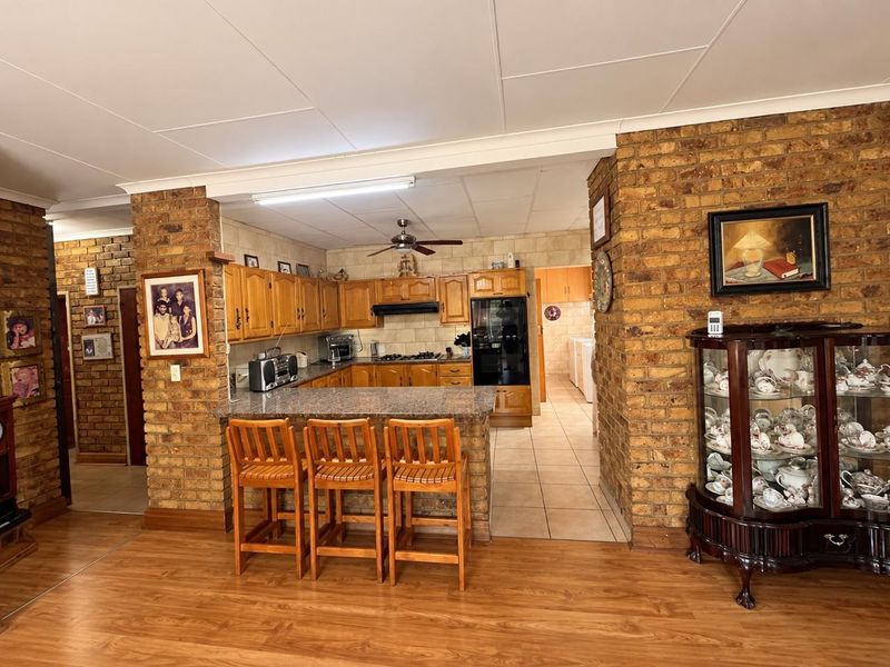 Open plan kitchen featuring exposed brick walls, granite breakfast bar, wooden cabinetry, and integrated appliances, seamlessly connecting to the living area.
