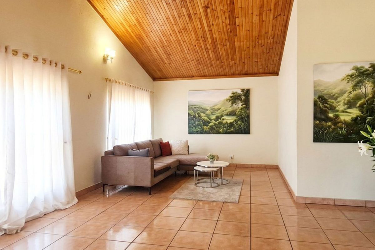 Spacious living room featuring a high vaulted timber ceiling, ceramic tiled flooring, and a classic archway entrance.