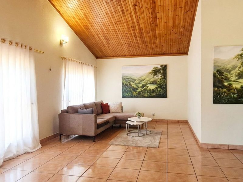 Spacious living room featuring a high vaulted timber ceiling, ceramic tiled flooring, and a classic archway entrance.