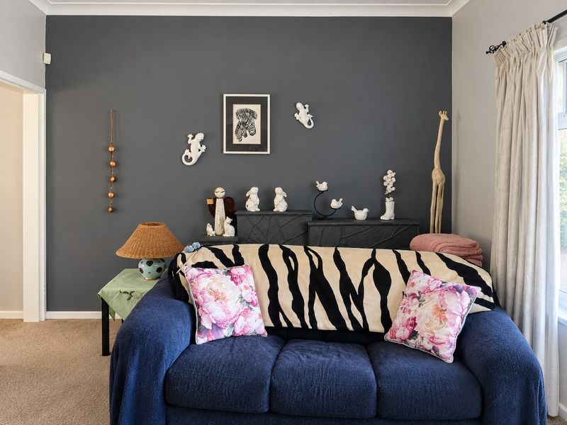 A living room featuring a dark grey accent wall, neutral carpeting, and window treatments.