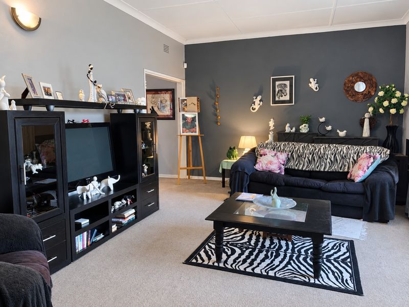 A comfortable living room featuring neutral and dark accent walls, carpeted flooring, and decorative coving.