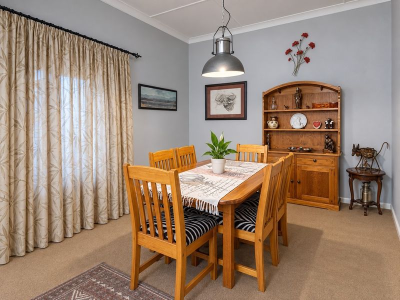 A dining room featuring neutral wall paint, carpeted flooring, and a central pendant light fixture.