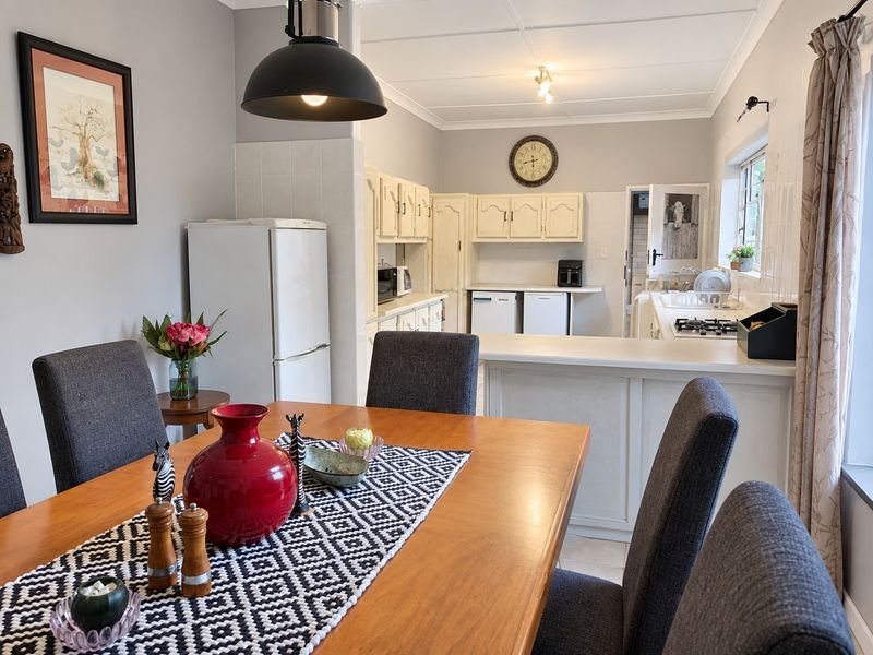 Open-plan dining area flowing into a functional kitchen featuring built-in cabinetry, a gas hob, and a breakfast counter.