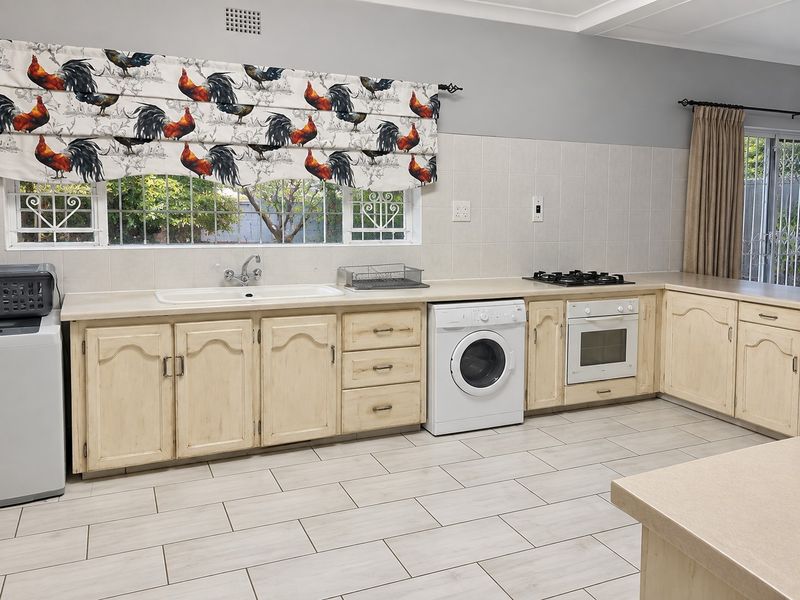Kitchen featuring light-toned cabinetry, gas hob, built-in oven, double sink, and tiled flooring with a neutral backsplash.
