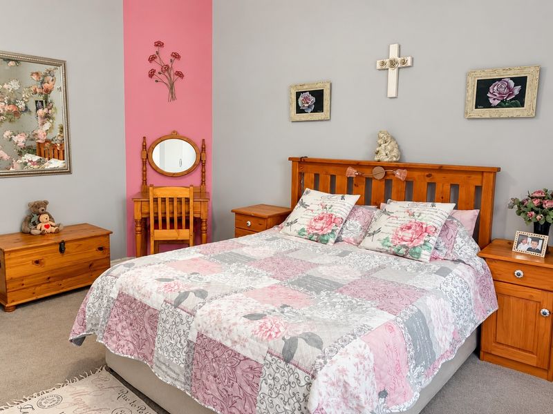 A carpeted bedroom featuring a neutral wall palette with a decorative pink accent wall.