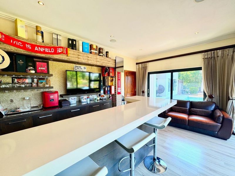 A well-appointed home bar area featuring a sleek built-in counter, custom cabinetry, and direct access to the outdoor pool area through sliding glass doors.