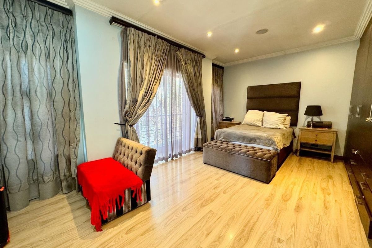 Spacious bedroom featuring light-toned laminate flooring, recessed ceiling lighting, and large sliding glass doors providing access to an outdoor area.