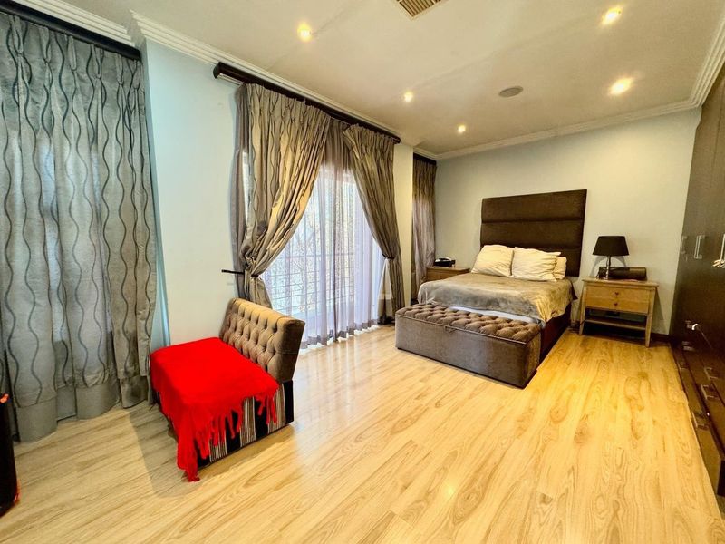 Spacious bedroom featuring light-toned laminate flooring, recessed ceiling lighting, and large sliding glass doors providing access to an outdoor area.