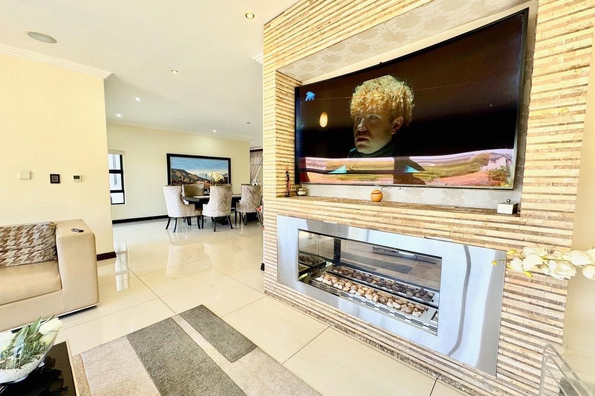 Spacious living area featuring a modern stone-clad feature wall with a built-in fireplace and integrated television recess, complemented by polished tiled flooring.