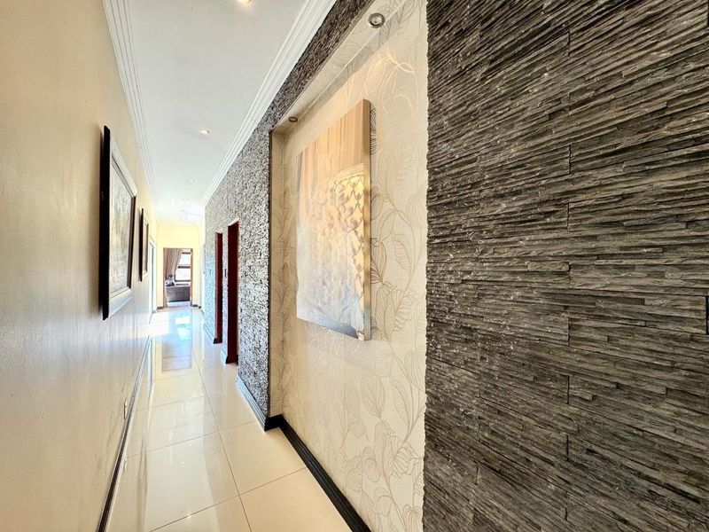 A well-maintained hallway featuring polished porcelain floor tiles, a textured stone cladding feature wall, and recessed ceiling lighting.