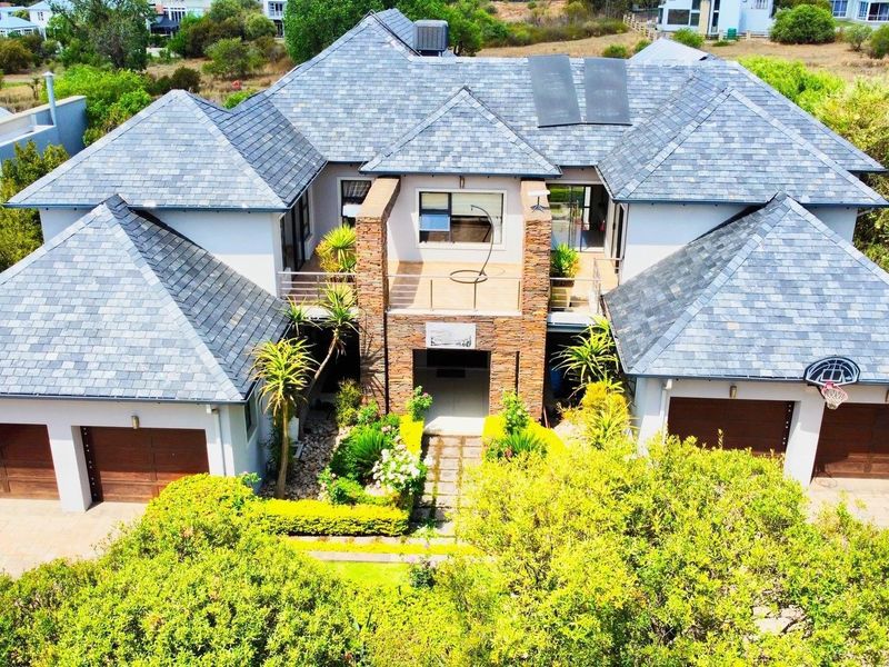 Aerial view of a large multi-level residential property featuring a slate tile roof, stone facade accents, and a spacious triple garage.