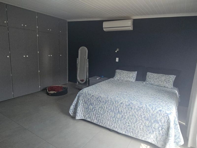 Spacious bedroom featuring large built-in cupboards, tiled flooring, and a wall-mounted split-system air conditioner.