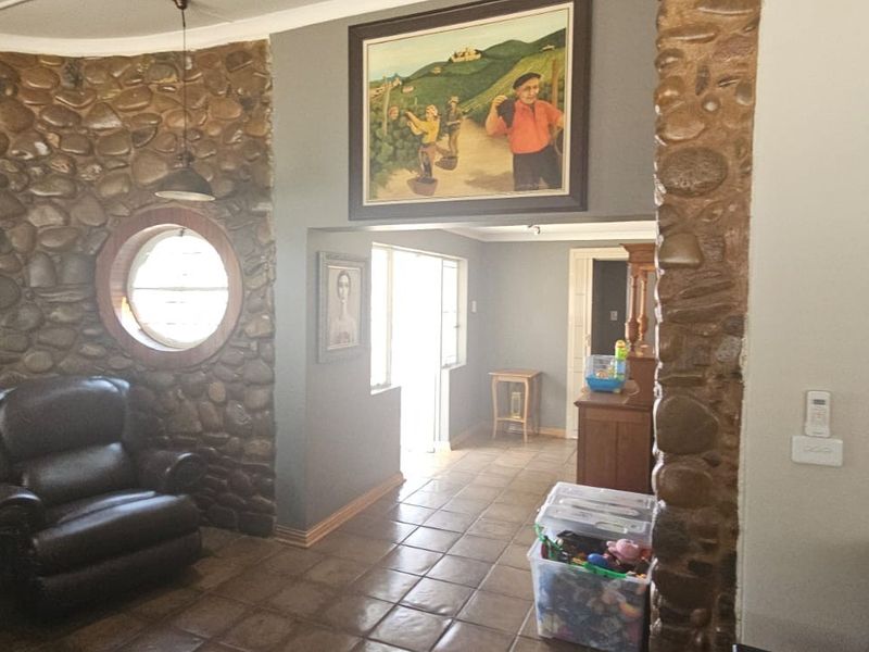 Living room featuring a distinctive stone feature wall, circular porthole window, and ceramic tile flooring, creating a rustic and character-filled interior space.
