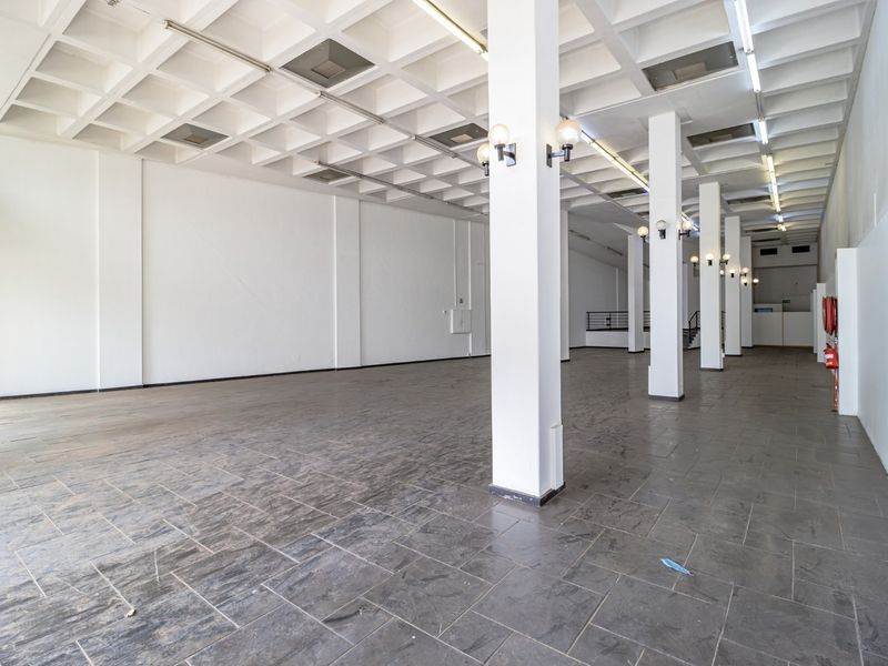 A spacious, open-plan commercial interior featuring a distinctive waffle slab ceiling, structural columns, and durable tiled flooring, suitable for various retail or office layouts.