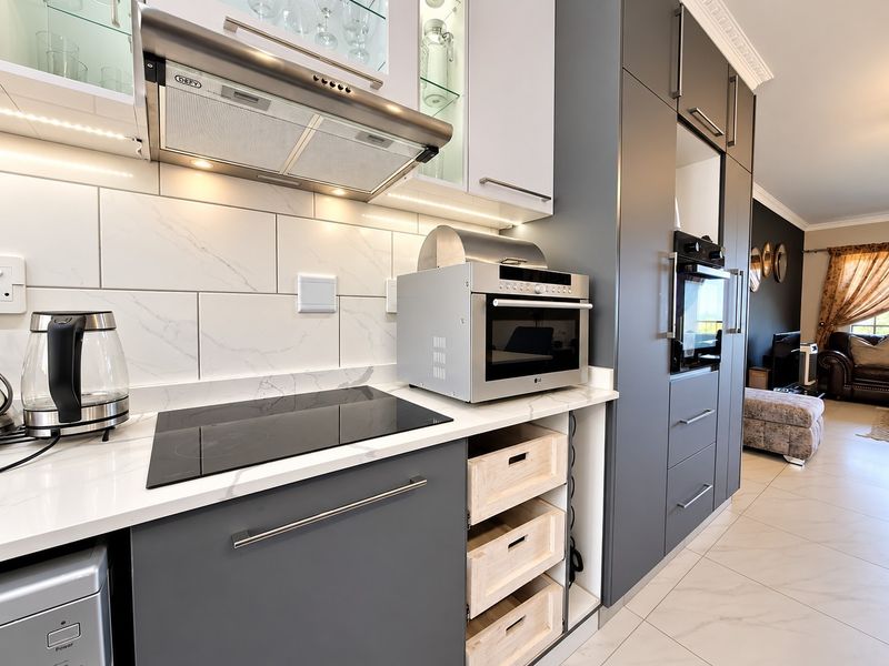 Modern kitchen featuring sleek grey cabinetry, marble-look countertops, subway tile backsplash, integrated oven, and high-quality porcelain floor tiles.