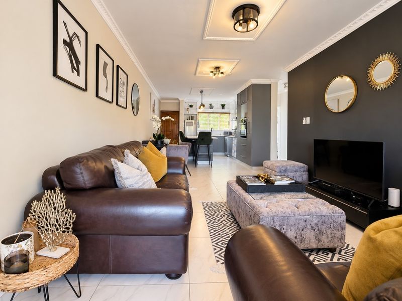A well-maintained open-plan living and kitchen area featuring modern cabinetry, tiled floors, and decorative ceiling detailing.