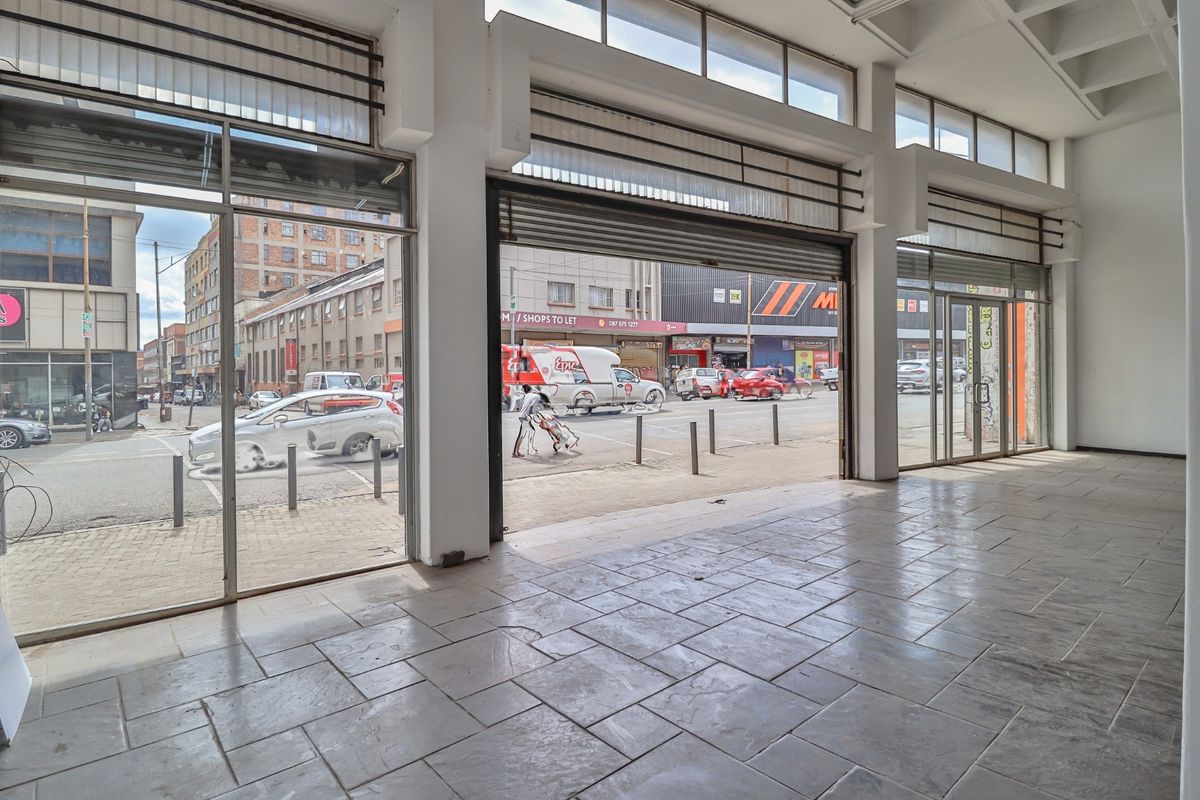 Spacious open-plan commercial retail unit featuring large glass storefront windows, tiled flooring, and high ceilings with exposed structural beams, offering excellent street visibility.