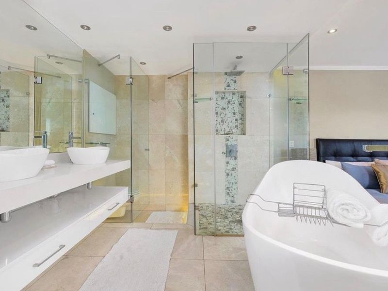 Modern open-plan bathroom featuring a sleek double vanity, a contemporary freestanding bathtub, and a spacious glass-enclosed shower with stone tile finishes.