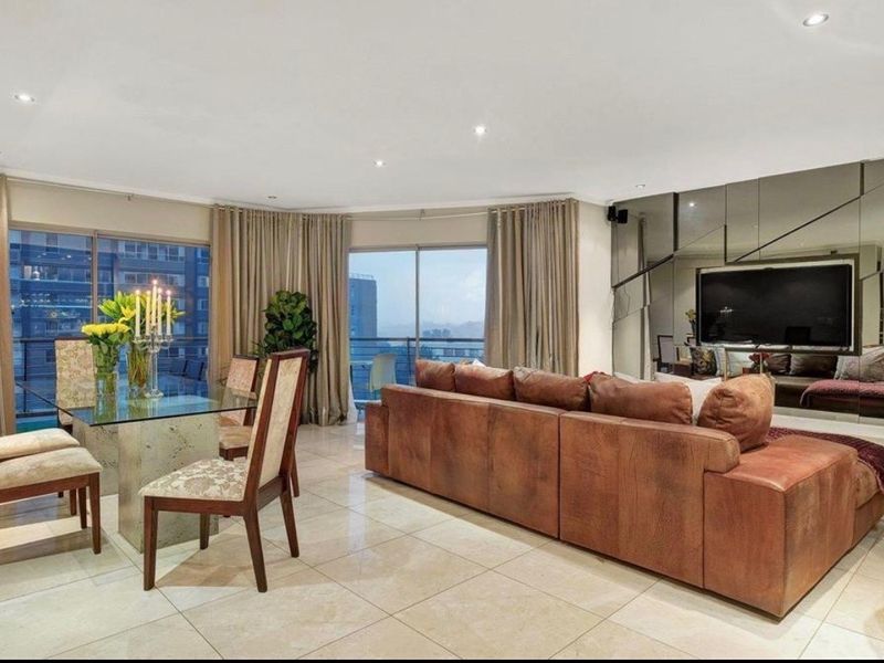 Spacious open-plan living and dining area featuring large sliding glass doors, tiled flooring, recessed lighting, and a decorative mirrored feature wall.