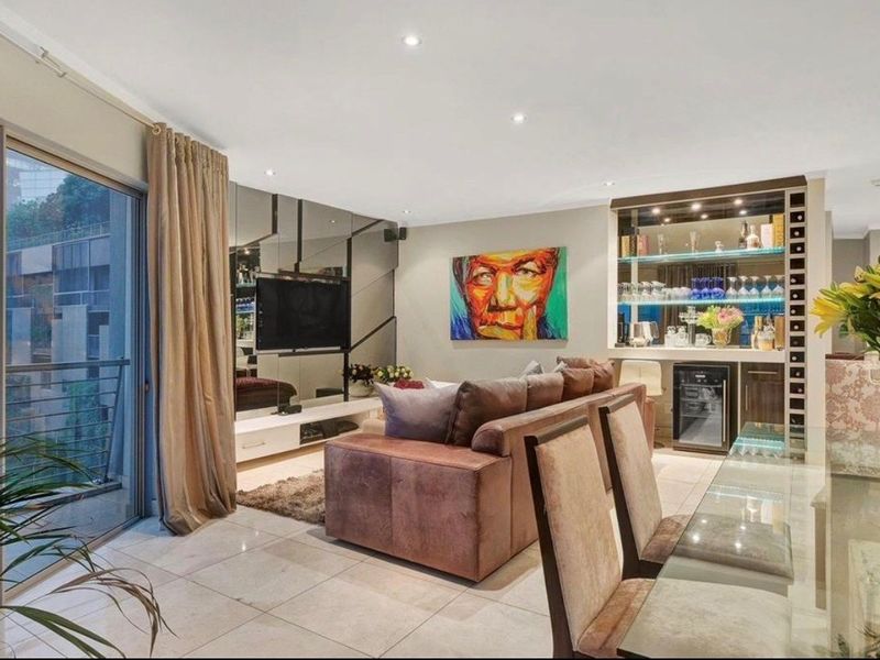 Open-plan living area featuring tiled floors, a mirrored feature wall, and a built-in bar with integrated wine storage and cabinetry.