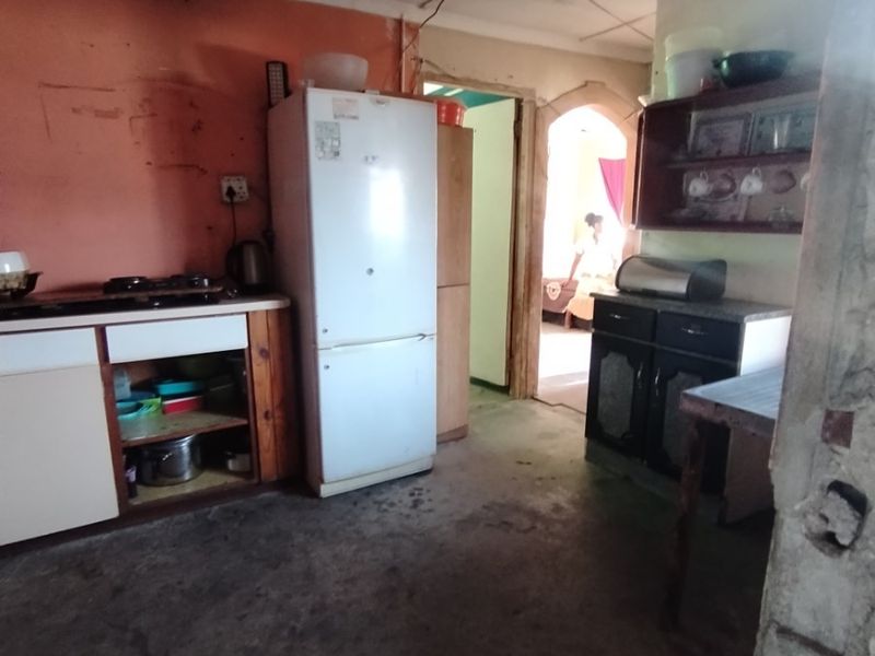 A dated kitchen area featuring built-in cabinetry and a cooktop, currently showing significant ceiling water damage and requiring extensive renovation.