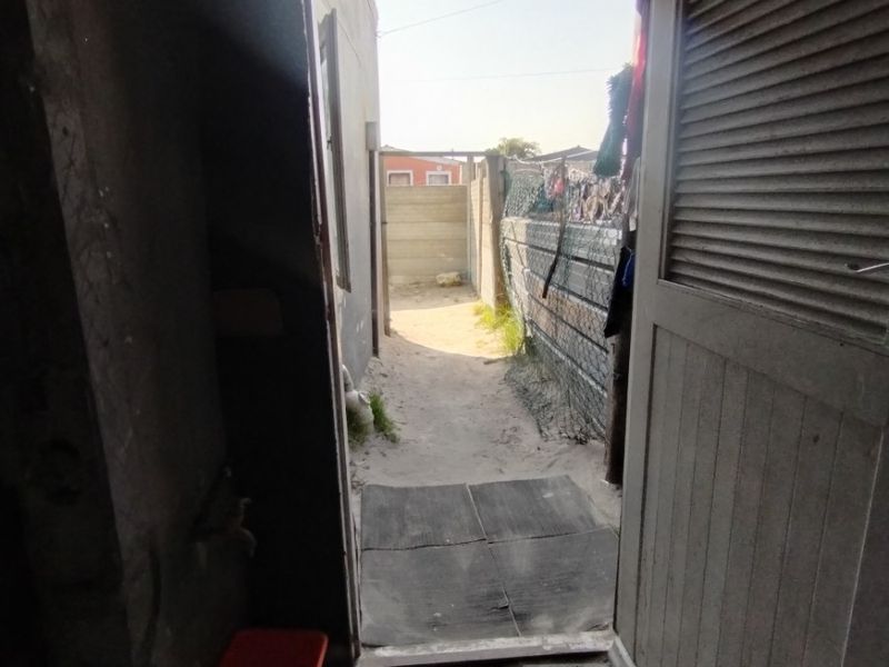 A utility space or back entrance area featuring a louvered door, concrete flooring, and direct access to the rear exterior yard.