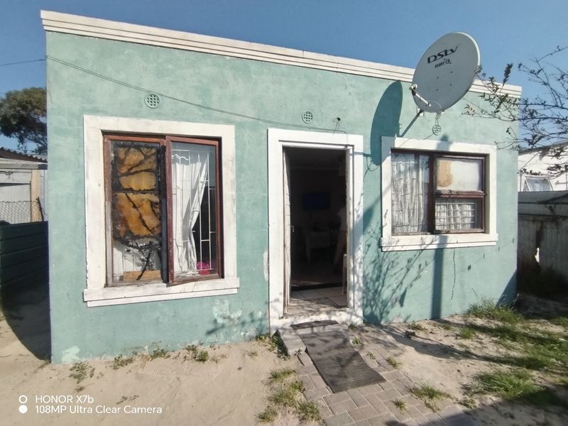 Front elevation of a single-story house featuring a satellite dish, security bars on windows, and a paved entrance path.