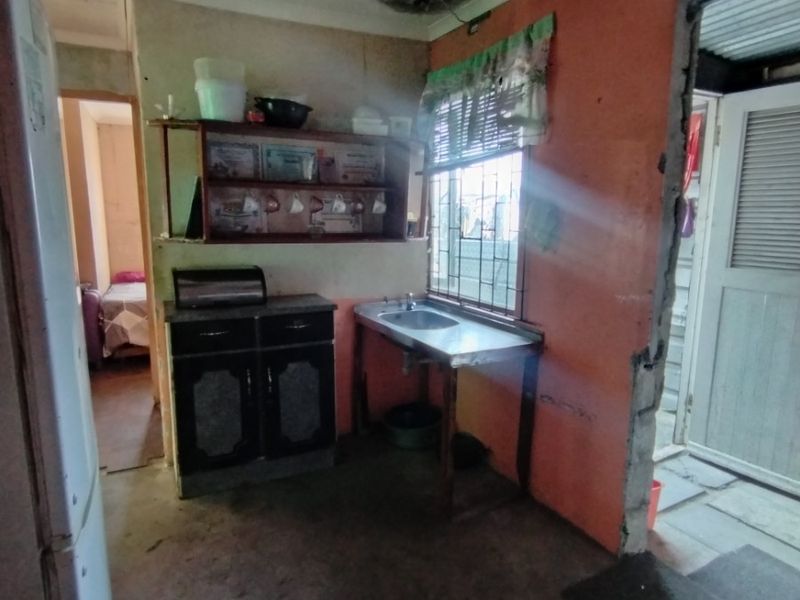 A small kitchen area featuring a stainless steel sink and built-in cabinetry, currently requiring significant ceiling repairs and general renovation to improve the space.